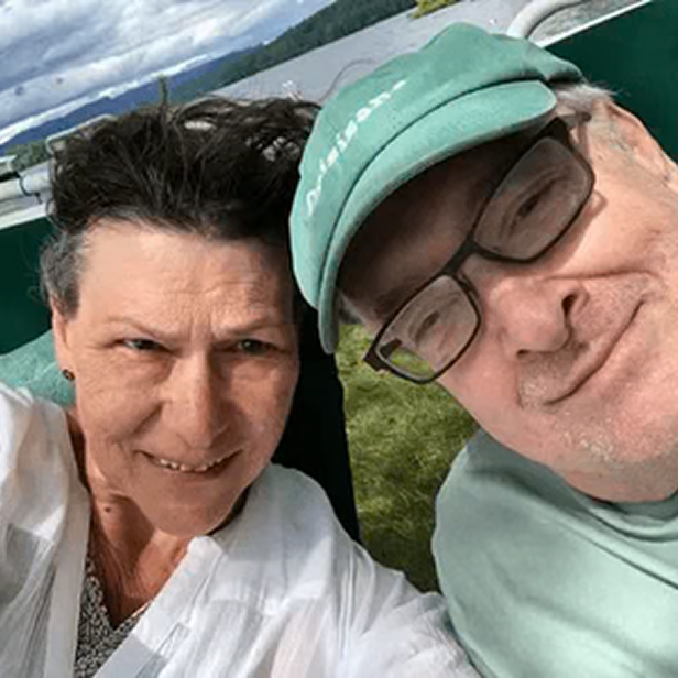 Smiling senior couple outdoors taking selfie, sharing positive experience with Audien hearing aids

